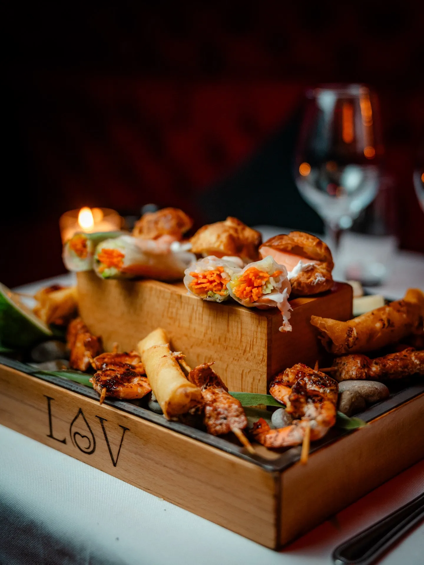 Spring rolls and skewers served on a branded LOV board